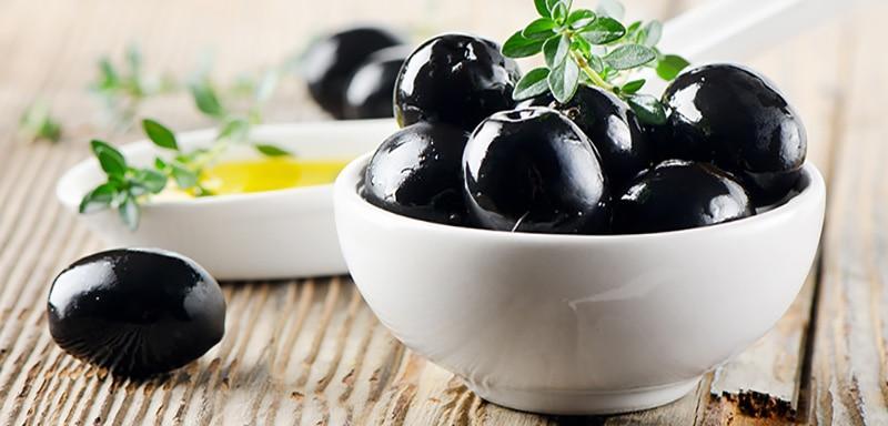 bowl of black olives with spoon of olive oil