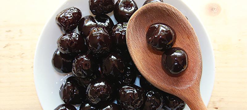 bowl of amarena cherries on wooden spoon