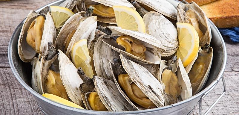 Bucket of sea clams with lemon wedges