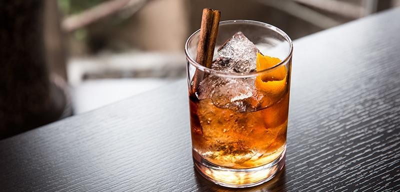 Glass of whiskey on the rocks with cinnamon stick