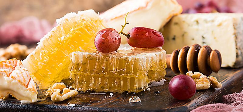 raw honeycomb with grapes, walnuts, brie and blue cheese on cheese board