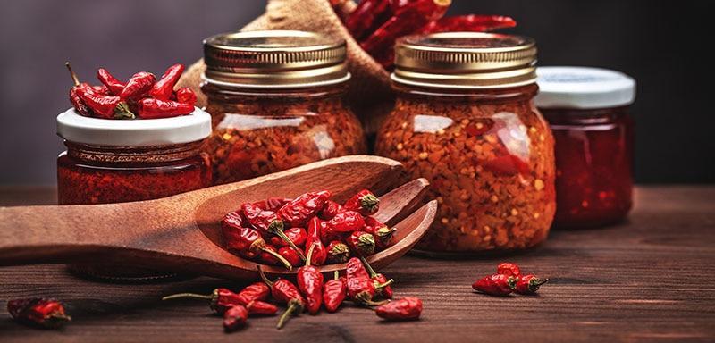 Red chili pepper sauce jars with raw red peppers