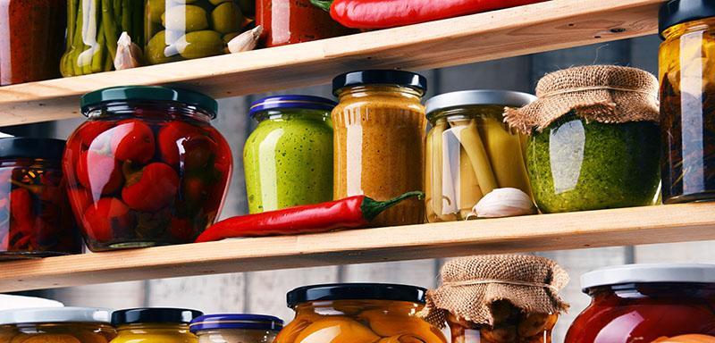 Pantry items olive spread, peppers, basil pesto, olives