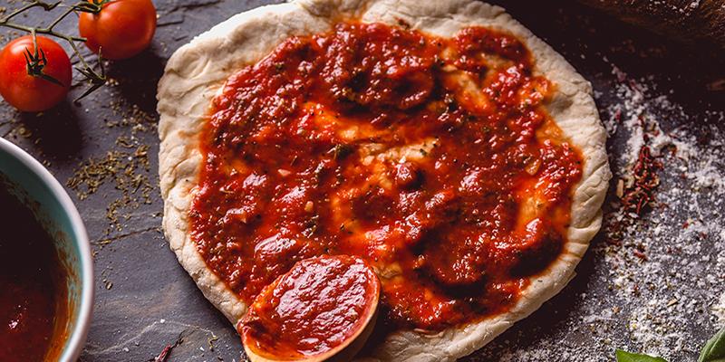 Pizza sauce on fresh pizza dough