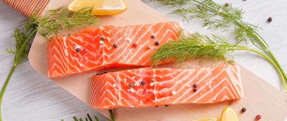 Fresh salmon on wooden cutting board with herbs and lemon